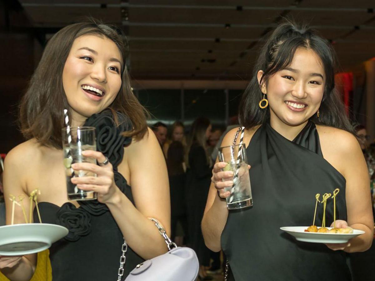 Two young women enjoying drinks and appetizers at a gala event