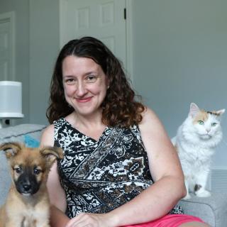 Foster sitting on a couch with a cat and puppy.