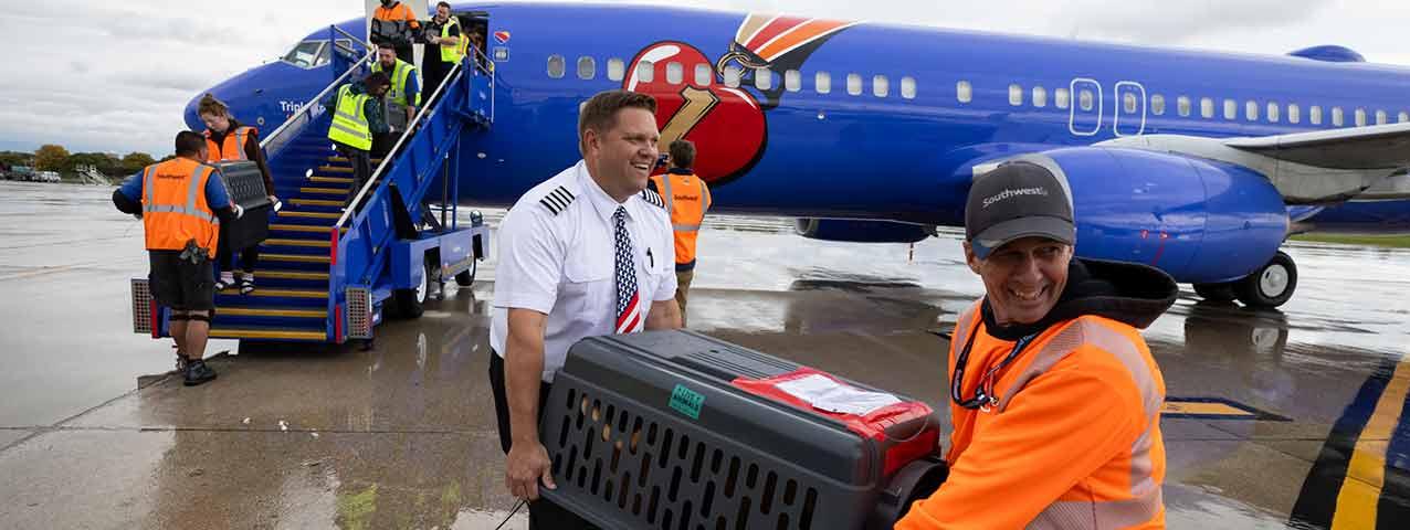 Southwest Airlines Captain Matt Prebish loading kennels onto a plane on a tarmac